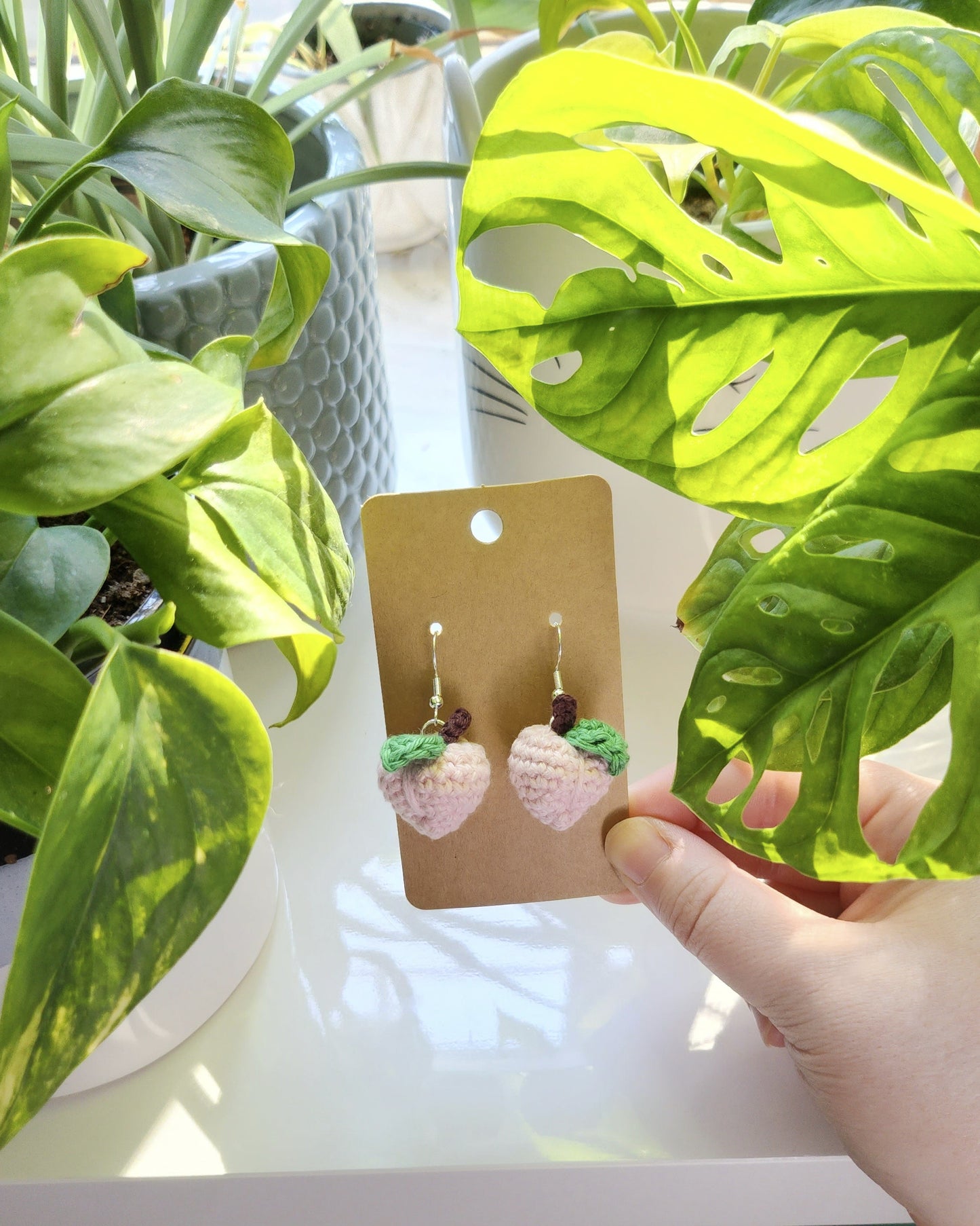 Hand holding a card with earrings near green plants