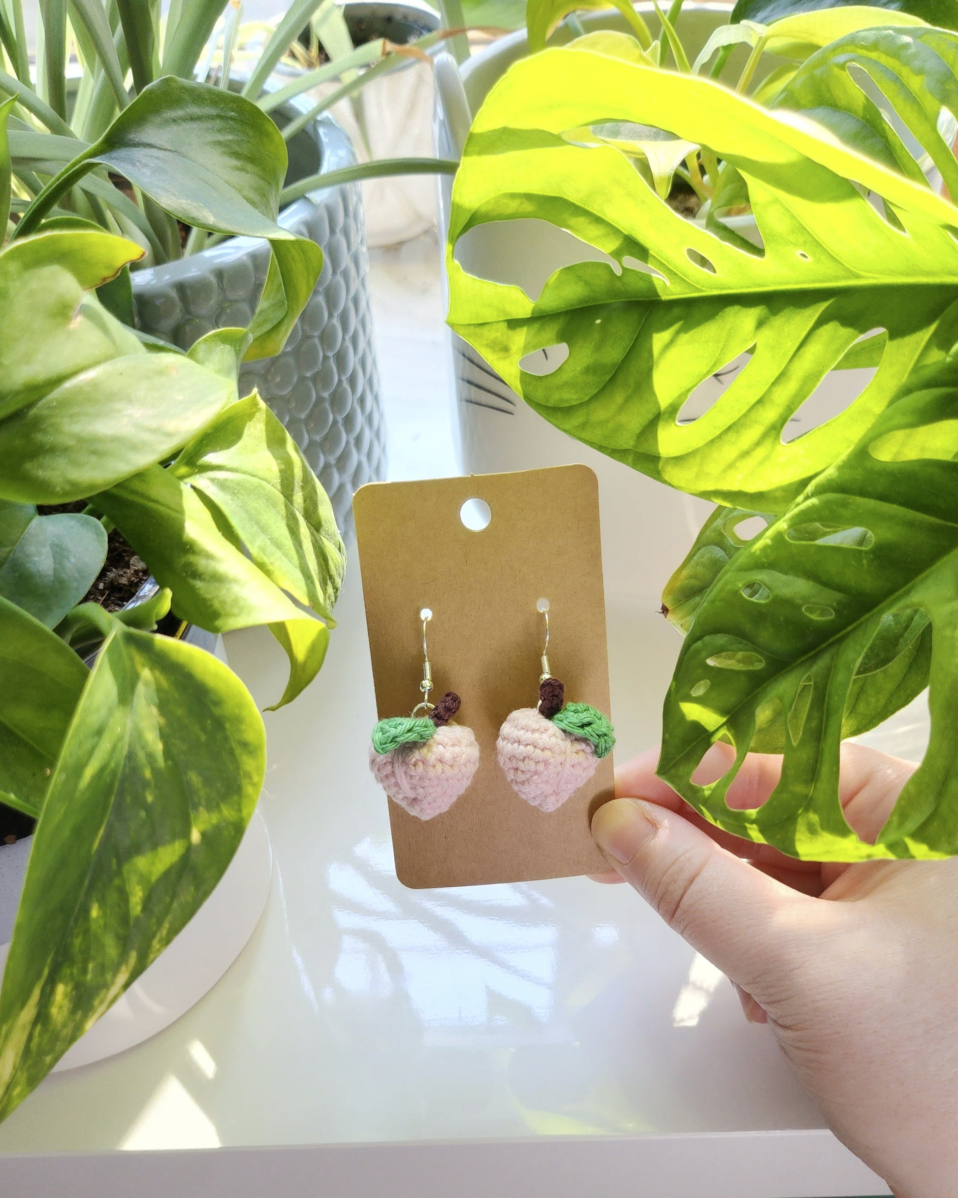 Hand holding a card with earrings near green plants