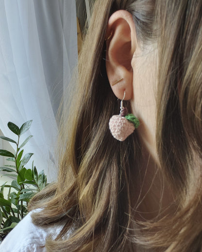 Close-up of a person's ear with peach earrings in.