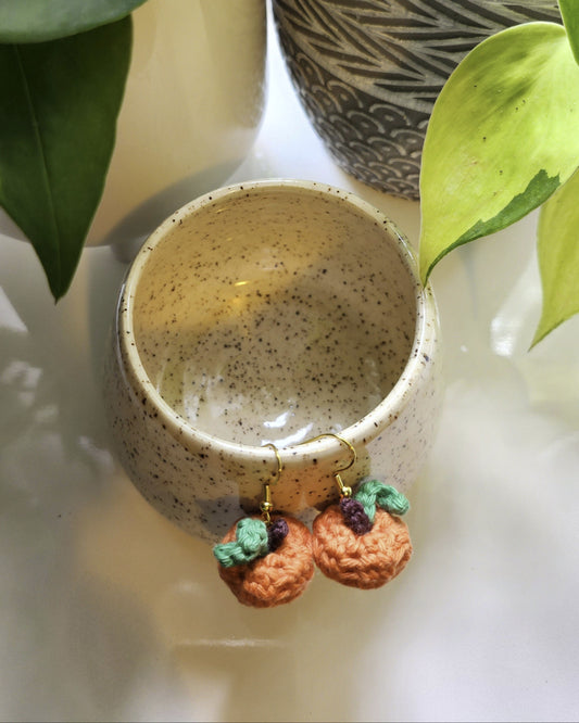 Small ceramic bowl with decorative elements on a light surface, surrounded by green leaves.