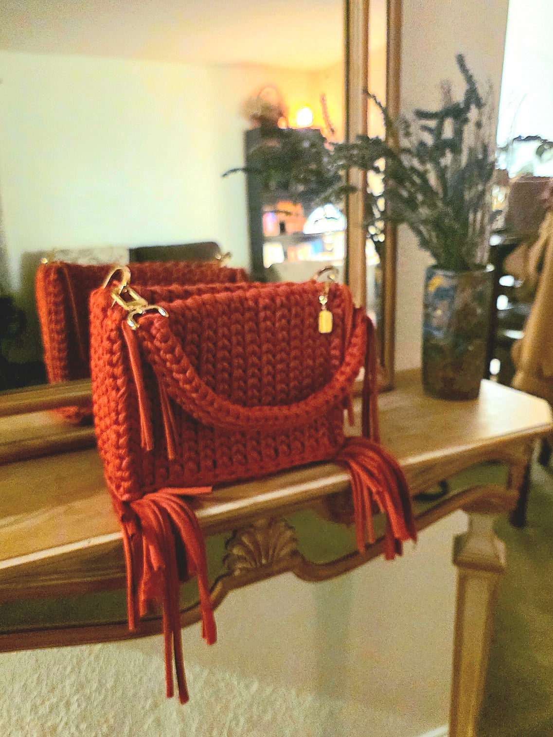Red crochet handbag with tassels on a wooden surface
