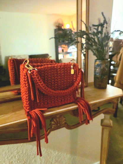 Red crochet handbag with tassels on a wooden surface