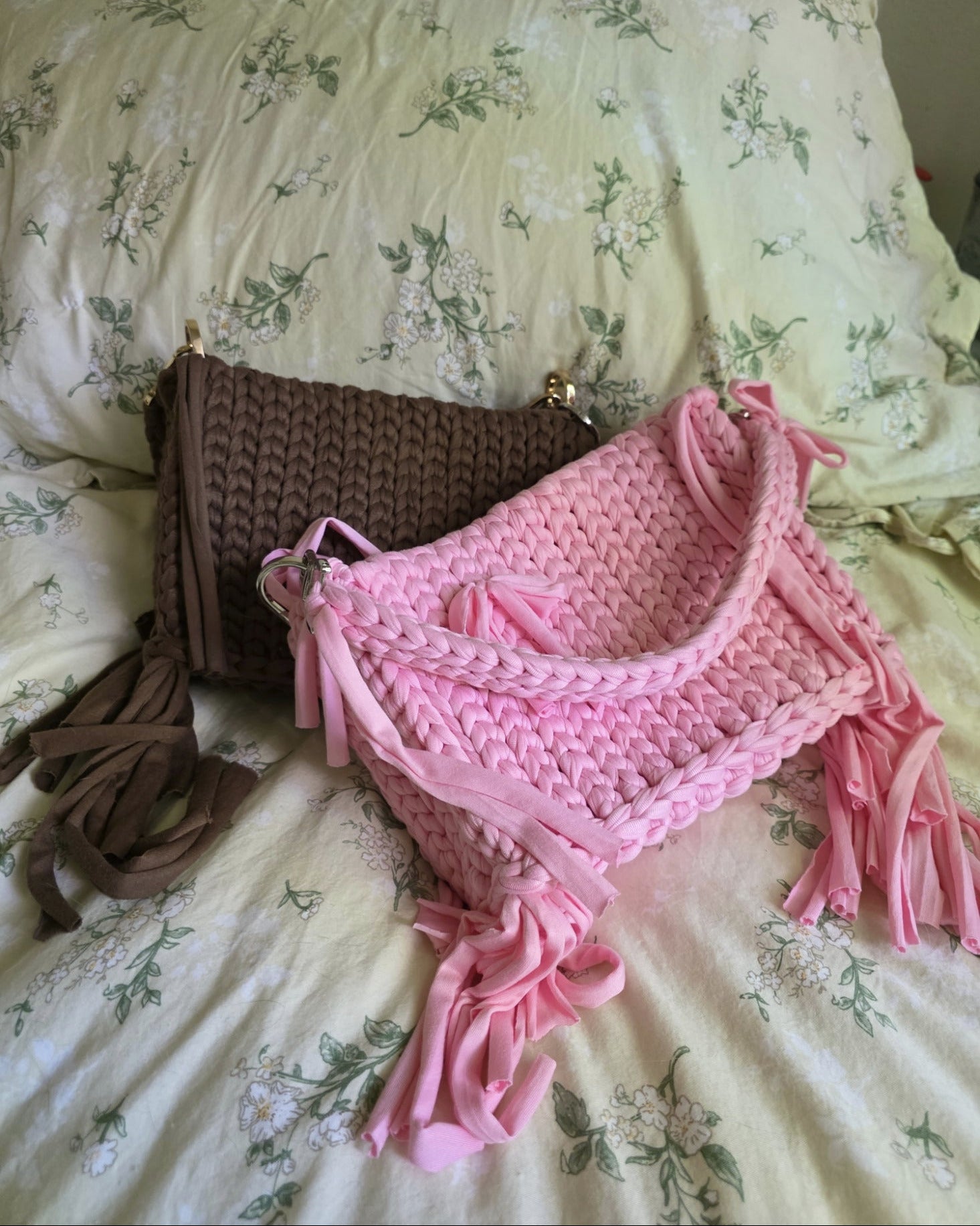 Pink and brown crocheted bag with tassels on a floral bedspread
