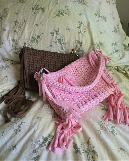 Pink and brown crocheted bag with tassels on a floral bedspread